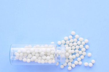 Close up homeopatik globüller ve mavi arka plan üzerinde cam şişe. Alternatif Homeopati ilaç otlar, şifalı bakım ve hap kavramı. Düzlay. Üst te. metin için copyspace