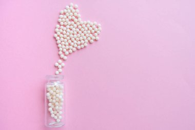 Kalp pembe arka plan üzerinde homeopatik globüller ve cam şişe yapılmış. Alternatif Homeopati ilaç otlar, şifalı bakım ve hap kavramı. Düzlay. Üst te. metin için copyspace