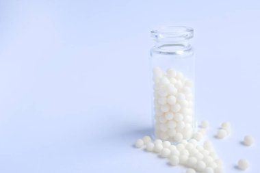 Close up homeopatik globüller ve mavi arka plan üzerinde cam şişe. Alternatif Homeopati ilaç otlar, şifalı bakım ve hap kavramı. Düzlay. metin için copyspace