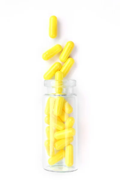 Žluté kapsle ze skleněné láhve na bílém podkladu. copyspace pro text. Epidemie, léky proti bolesti, zdravotní péče, prášky na léčbu a zneužívání drog — Stock fotografie
