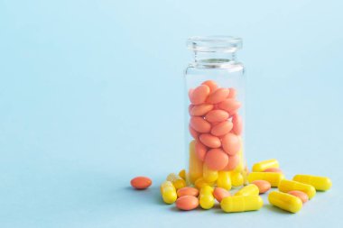 Mavi arka plan üzerinde cam şişe sarı ve turuncu kapsüller. metin için copyspace. Salgın, ağrı kesiciler, sağlık, tedavi hapları ve uyuşturucu bağımlılığı kavramı