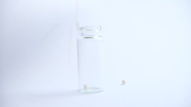 Cam şişe mavi arka plan üzerinde homeopatik beyaz globüller ile dolduruyor. Alternatif Homeopati ilaç otlar, şifalı bakım ve hap kavramı.
