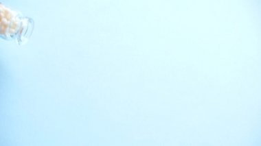 cam şişeden mavi arka plan üzerinde homeopatik globüller rulo. Alternatif Homeopati ilaç otlar, şifalı bakım ve hap kavramı. Üstte görüntü.