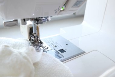 İşyerinde beyaz kumaş tekstil ile dikiş makinesini kapatın. Dikiş işlemi. - iğne, zanaat, dikiş ve terzilik konsepti