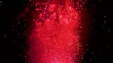 Renkli fişek ışıkları yakın çekim patlıyor. Göz kamaştırıcı havai fişekler gece siluetini yayıyor. Festival ve kutlama arka plan.