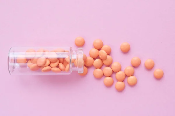 Oranžové tablety ze skleněné láhve na růžovém pozadí. copyspace pro text. Epidemie, léky proti bolesti, zdravotní pilulky a koncepce zneužívání drog. ležel rovně. pohled shora — Stock fotografie