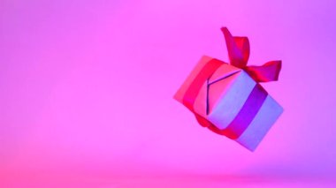 Neon mor arka plan üzerinde dönen kırmızı kurdele ile Hediye kutusu. 360 derece dönüş. sorunsuz döngü. sıfır yerçekimi. Levitation. copyspace. Konsept satış, indirimli fiyat, noel tatilleri ve alışveriş.