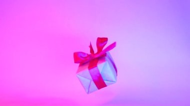 Neon mor arka plan üzerinde dönen kırmızı kurdele ile Hediye kutusu. 360 derece dönüş. sorunsuz döngü. sıfır yerçekimi. Levitation. copyspace. Konsept satış, indirimli fiyat, noel tatilleri ve alışveriş.