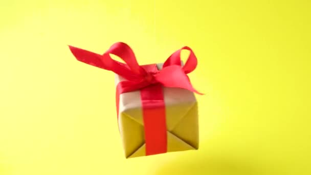 礼品盒 红色缎带 黄色背景旋转 360度旋转 无缝循环 零重力升空 概念销售 折扣价 圣诞节假期和购物 — 图库视频影像