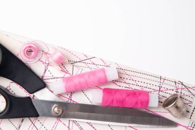 Beyaz arka planda çok renkli iplik bobinleri ve ölçme bandı. Dikişler, dikiş, nakış için dikiş malzemeleri yüksük makas, desen ve aksesuarlar. boşaltmak. düz yatıyordu, üst görünüm