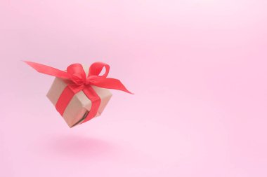 Pembe arka planda kırmızı kurdele ile hediye kutusu. sıfır yerçekimi. Levitation. milimalizm. boşaltmak. Konsept satış, alışveriş, yılbaşı tatili ve Doğum günü
