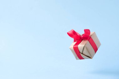 Mavi arka planda kırmızı kurdele ile hediye kutusu. sıfır yerçekimi. Levitation. milimalizm. boşaltmak. Konsept satış, alışveriş, yılbaşı tatili ve Doğum günü