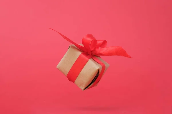 红色背景上带红丝带的礼品盒。零重力。悬浮。军事主义。概念销售、购物、圣诞假期和生日 — 图库照片