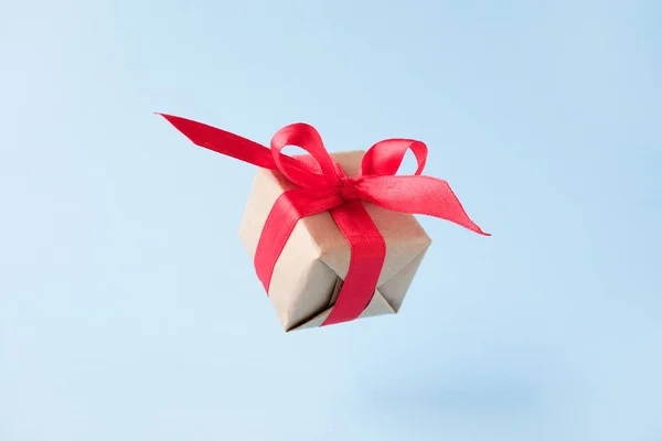 Κουτί δώρου με κόκκινη κορδέλα σε μπλε φόντο. μηδενική βαρύτητα. Μετεωρισμού. του μεταλιματισμού. Έννοιες πωλήσεις, ψώνια, Χριστουγεννιάτικες διακοπές και γενέθλια — Φωτογραφία Αρχείου