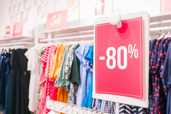 Sezon satış, black friday ve alışveriş konsepti. Kırmızı stand dükkanda yüzde 80 indirimli fiyat. Arka planda giysi askıları