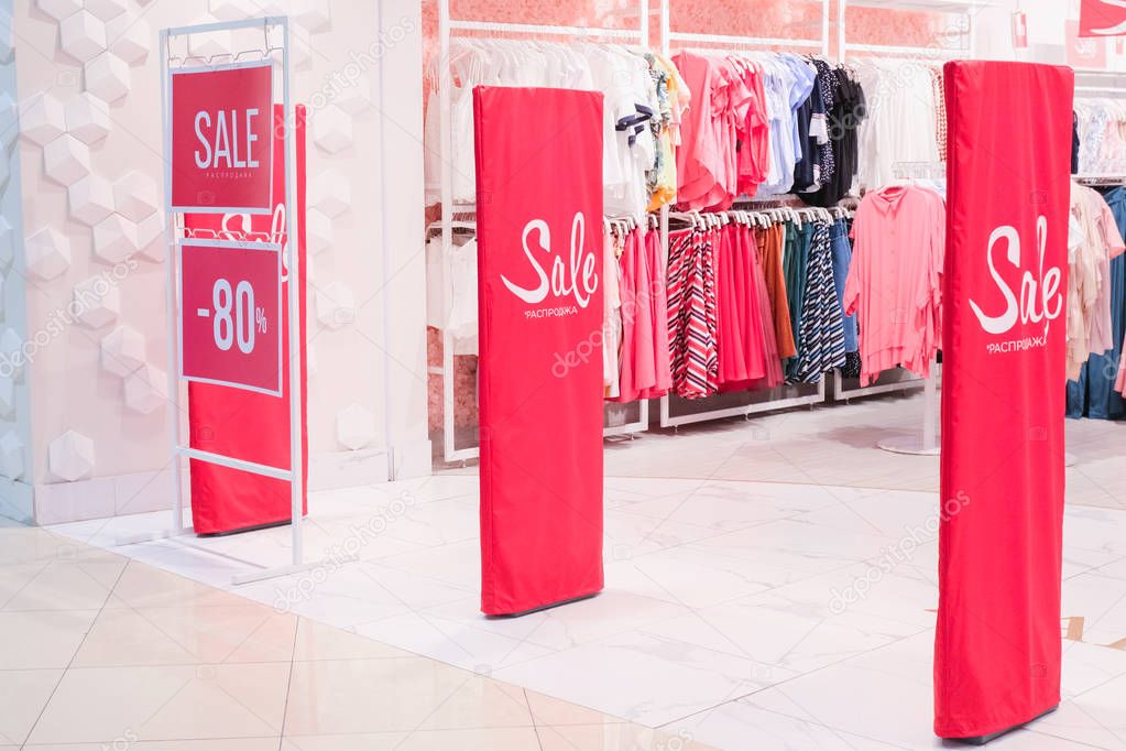 Season sale, black friday and shopping concept. Sale sign on red stand with 80 percent discount price in store shop. Clothes hangers on background.