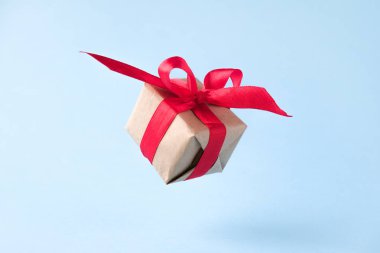 Mavi arka planda kırmızı kurdele ile hediye kutusu. sıfır yerçekimi. Levitation. milimalizm. Konsept satış, alışveriş, yılbaşı tatili ve Doğum günü