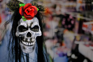 Bulanık arka planda kırmızı gül olan ürkütücü Cadılar Bayramı İnsan Kafatası. Karanlık bir görüntü. Kopyalama alanı - tatiller, dekorasyon ve parti konsepti