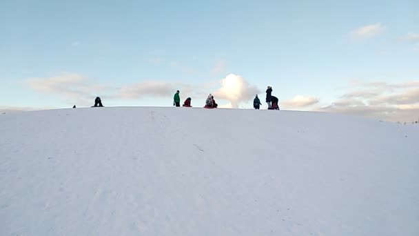 Drie kinderen in rode kleren glijden van de heuvel af. Kinderen sleeën bergafwaarts. Familie vakantie, skivakantie. — Stockvideo