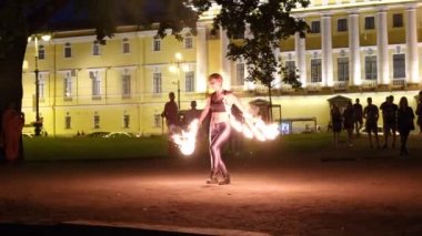 Turistler için yanan çubuklarla dans eden dansçı, açık havada karanlıkta alev saçıyor. Manzara yangını. Çekici profesyonel eğlence konsepti. Rusya St. Petersburg 27.08.19