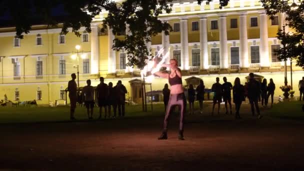 Dancer with flaming sparkling sticks for tourists, rotates flame on the darkness at open air. Scenery fireshow. Attractive professional entertaining concept. Russia St.Petersburg 27.08.19 — Stock Video