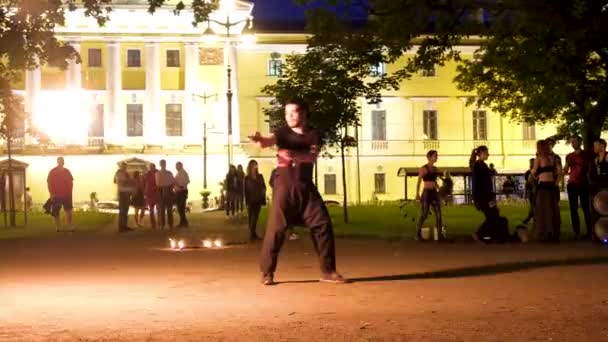 Turistler için yanan çubukları olan sokak sanatçısı açık havada karanlıkta alev saçıyor. Fireshow. Çekici profesyonel eğlence konsepti. Rusya St. Petersburg 27.08.19 — Stok video