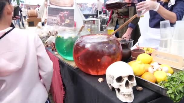 Halloween dryck - Flicka rör cocktail som kokande trolldryck med heta bubblor i glas kittel på halloween fest mässan — Stockvideo