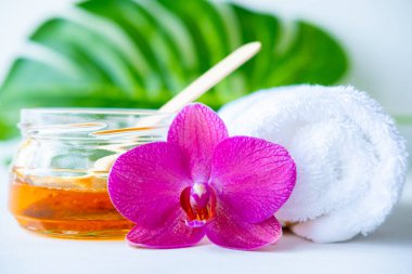 Tahta spatula çubuklarıyla saç kesimi için ballı ya da şekerli bal. çiçek arkaplanı - depilasyon ve güzellik konsepti