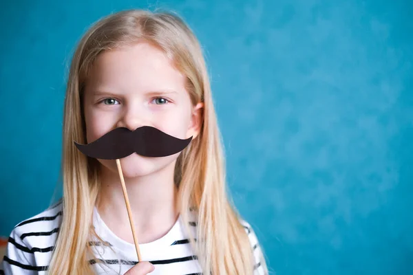 Menina loira criança engraçada com bigode no fundo azul. Espaço de cópia. Feliz dia do pai . — Fotografia de Stock