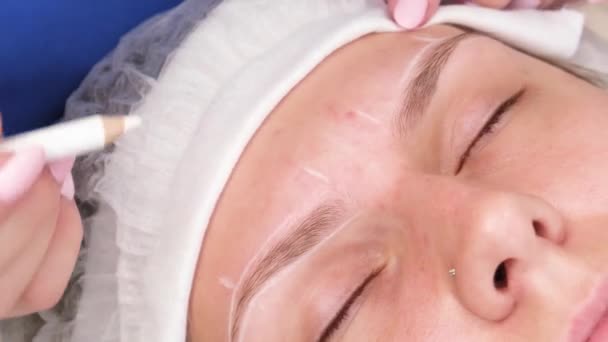 Maquillage permanent pour les sourcils de femme aux sourcils épais dans un salon de beauté. Gros plan esthéticienne faire coloriage tatouage sourcil — Video