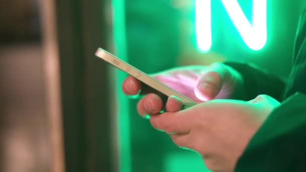  Les mains d'homme avec téléphone intelligent se rapprochent dans les néons branchés de la rue. Mode de vie. Facile à payer en ligne en utilisant un téléphone intelligent ou un appareil numérique. Communication via l'application à vendre dans le magasin. médias sociaux 