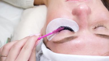 Kirpik uzatma prosedürünü kapatıyoruz. Güzellik uzmanı, güzellik salonundaki kadın müşterinin uzatma işleminden sonra uzun kirpiklerini hazır etti. 4k görüntü