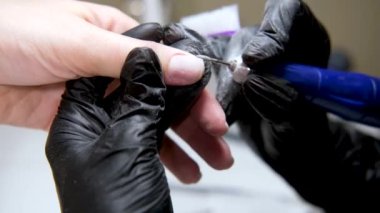 4 bin. Elektrikli cihaz kullanan donanım manikürü. Tırnak cilası sürmeden önce oje hazırlama prosedürü. Siyah eldivenli manikürcünün elleri ve müşteri tırnakları. Güzellik Salonundaki Kadın