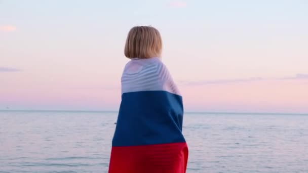 4k.Back uitzicht vrouw in de zomer kleding met nationale Rusland vlag buiten zee zonsondergang - Russische vlag, land, patriottisme, Rusland dag en 12 juni. — Stockvideo