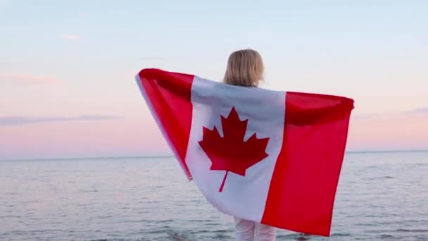 4k.Arrière vue femme en vêtements d'été avec drapeau national du Canada à l'extérieur océan coucher de soleil sur la mer - drapeau du Canada, pays, patriotisme, fête de l'indépendance et concept des personnes . — Video