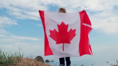 4 bin. Sarışın çocuk yazın mavi gökyüzünde ulusal Kanada bayrağını sallıyor - Kanada günü, ülke, vatanseverlik, bağımsızlık günü 1 Temmuz