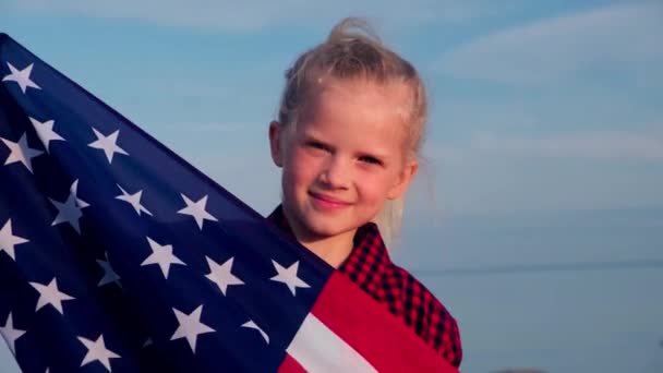 4k. Chica rubia ondeando bandera nacional de EE.UU. al aire libre sobre el cielo azul en verano bandera americana, país, patriotismo, día de la independencia 4 de julio . — Vídeos de Stock