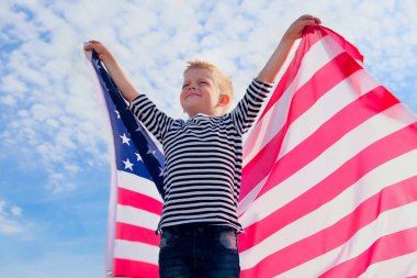 Sarışın çocuk yazın mavi gökyüzünde ulusal Amerikan bayrağı sallıyor - Amerikan bayrağı, ülke, vatanseverlik, bağımsızlık günü 4 Temmuz.