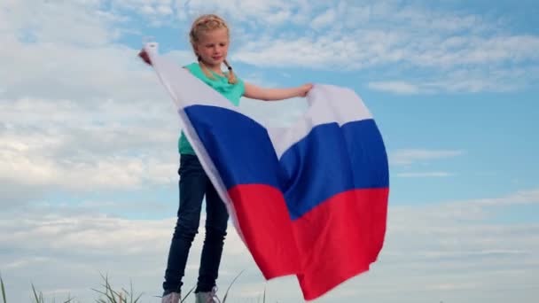 4k.Blond meisje zwaaien nationale Rusland vlag buiten boven de blauwe hemel in de zomer - Russische vlag, land, patriottisme, Rusland dag 12 juni. — Stockvideo