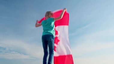 4 bin. Sarışın kız yazın mavi gökyüzünde ulusal Kanada bayrağını sallıyor - Kanada günü, ülke, vatanseverlik, bağımsızlık günü 1 Temmuz