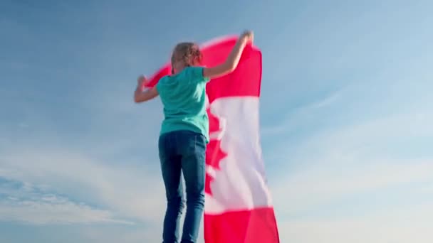 4k. Chica rubia ondeando bandera nacional de Canadá al aire libre sobre el cielo azul en verano - Día de Canadá, país, patriotismo, día de la independencia 1 de julio — Vídeos de Stock