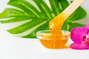 Tahta spatula çubuklarından akan tüyleri temizlemek için bal ya da şeker ezmesi. çiçek arkaplanı - tüy dökücü ve güzellik konsepti. kopyala