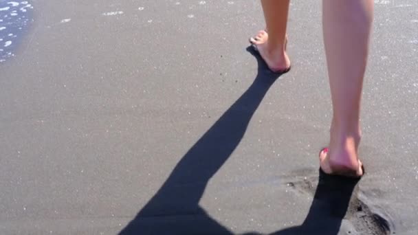 Femme marchant seule sur la plage de sable de l'océan laissant une empreinte dans le sable sombre. voyage Îles Canaries. Mouvement lent — Video