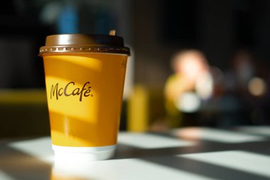 McDonalds restoranında McCafe menüsü. Masada sarı kahve fincanı ve güneşten gelen gölgeler. Kahvaltı zamanı, kahve zamanı. Finlandiya, Vantaa, 28 Şubat 2020