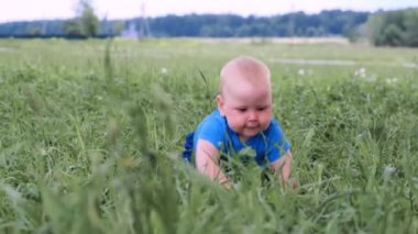 4 bin. Küçük beyaz bebek yeşil çimlerde sürünüyor ve geniş bir gülümsemeyle gülümsüyor. Mutlu çocukluk ve bebek sağlığı hizmetleri.