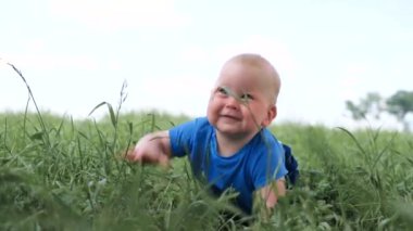 4 bin. Bebek yeşil çimlerde sürünüyor ve geniş bir gülümseme içinde. Heyecanlı, küçük beyaz bir çocuk. Mutlu çocukluk ve bebek sağlığı hizmetleri.