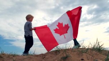 4 bin. Sarışın çocuk ve kız yazın mavi gökyüzünde ulusal Kanada bayrağı sallıyorlar - Kanada günü, ülke, vatanseverlik, bağımsızlık günü 1 Temmuz