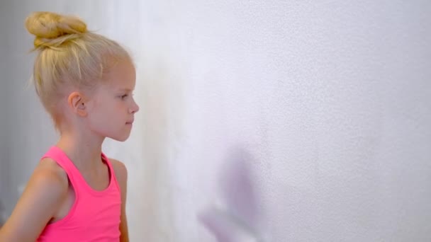 4K. menina loira fazendo reparos em casa pintura pintura rolo parede tinta branca. Renovação, interior da família . — Vídeo de Stock