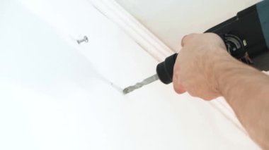 4 bin. İnsan ellerini elektrikli matkapla kapatarak evdeki beyaz beton duvarda delik açıyor - iç tasarım ve ev yenileme konsepti