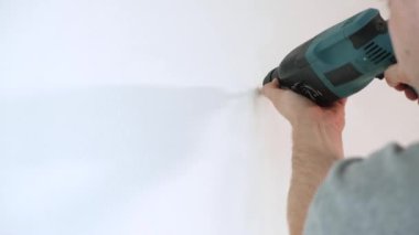 4 bin. İnsan ellerini elektrikli matkapla kapatarak evdeki beyaz beton duvarda delik açıyor - iç tasarım ve ev yenileme konsepti